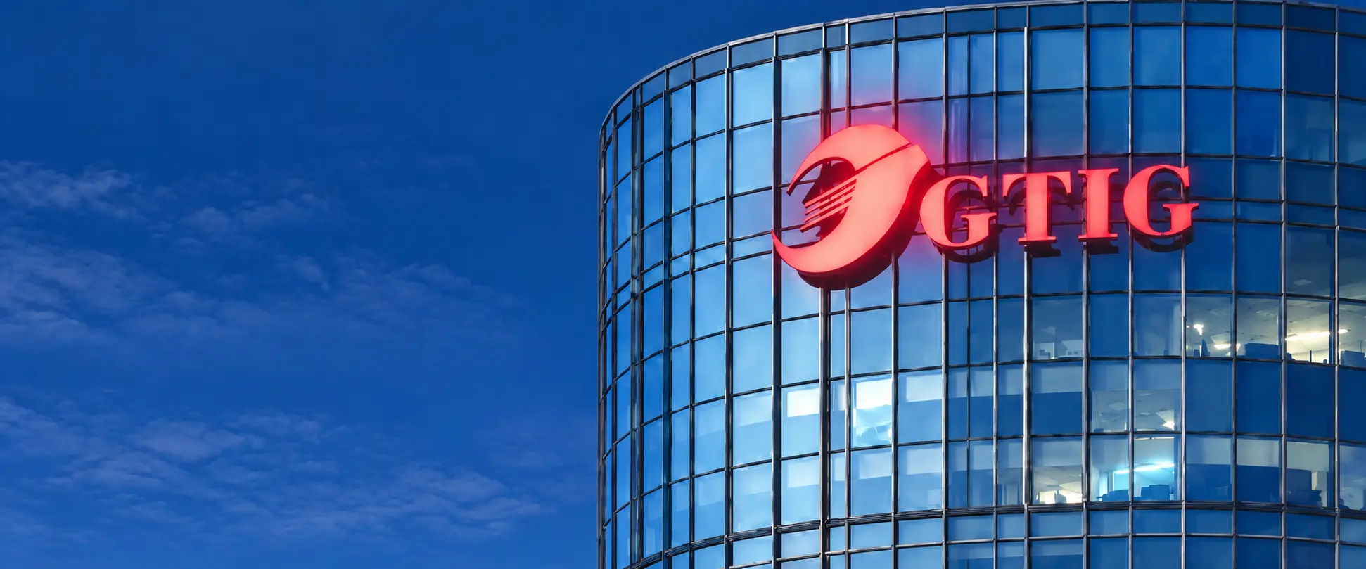Illuminated GTIG sign on the group headquarters tower at dusk